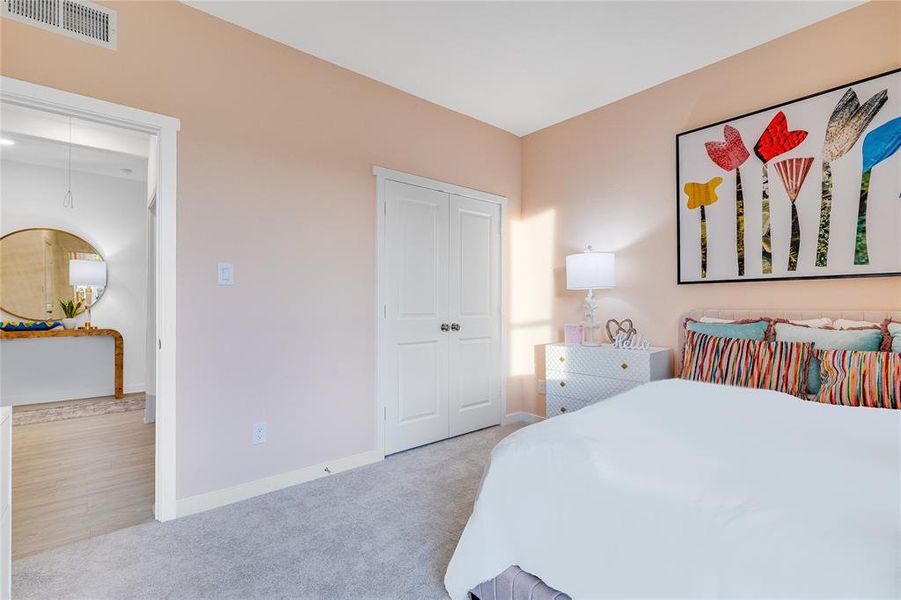 Bedroom featuring a closet, visible vents, light carpet, and baseboards