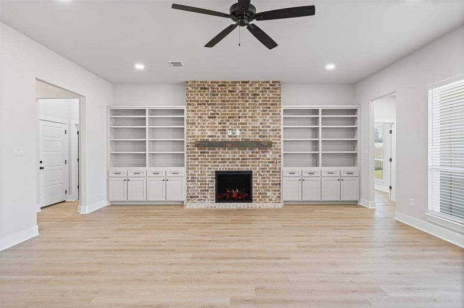Unfurnished living room featuring a fireplace, light wood-style flooring, a ceiling fan, and recessed lighting Unfurnished living room featuring a fireplace, light wood-style flooring, a ceiling fan, and recessed lighting