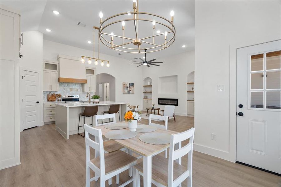 Dining room featuring a chandelier, arched walkways, recessed lighting, light wood-style floors, and a glass covered fireplace Dining room featuring a chandelier, arched walkways, recessed lighting, light wood-style floors, and a glass covered fireplace