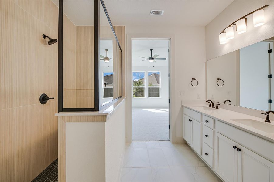 Bathroom featuring walk in shower, double vanity, and light tile patterned floors