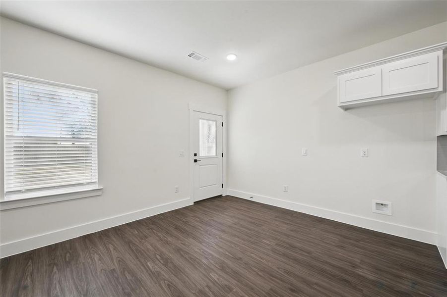 Spare room featuring baseboards, visible vents, and dark wood-style flooring Spare room featuring baseboards, visible vents, and dark wood-style flooring