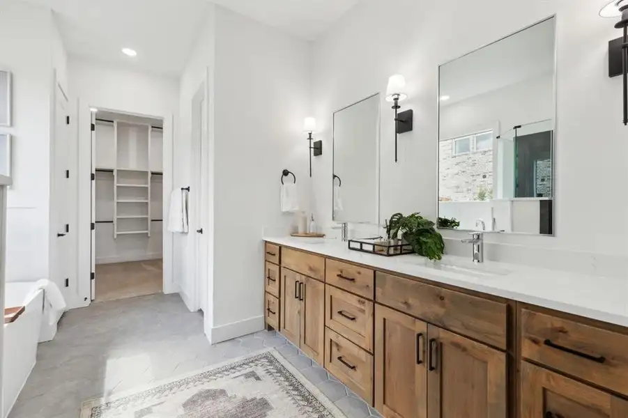 Bathroom with double vanity, a soaking tub, a walk in closet, recessed lighting, and light tile patterned floors