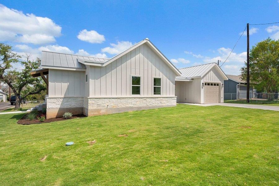 The property features a white exterior with vertical siding and a stone base, complemented by a light gray metal roof