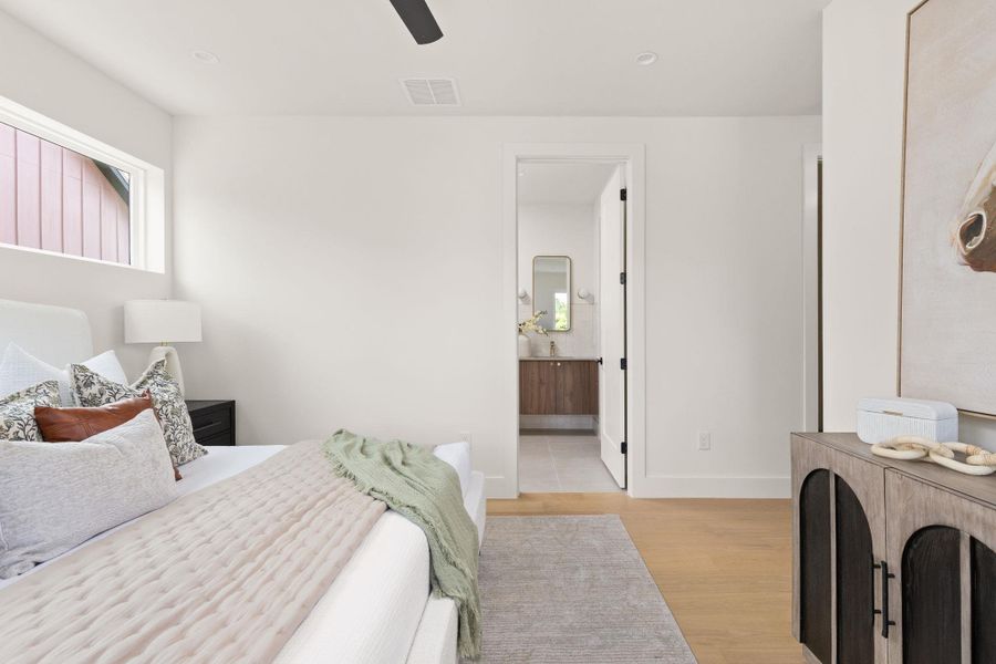 A tranquil bedroom retreat features warm wood flooring and an ensuite bathroom for ultimate convenience. A tranquil bedroom retreat features warm wood flooring and an ensuite bathroom for ultimate convenience.