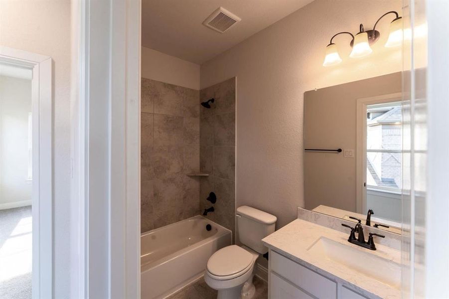 Full bathroom featuring vanity, tiled shower / bath combo, and toilet