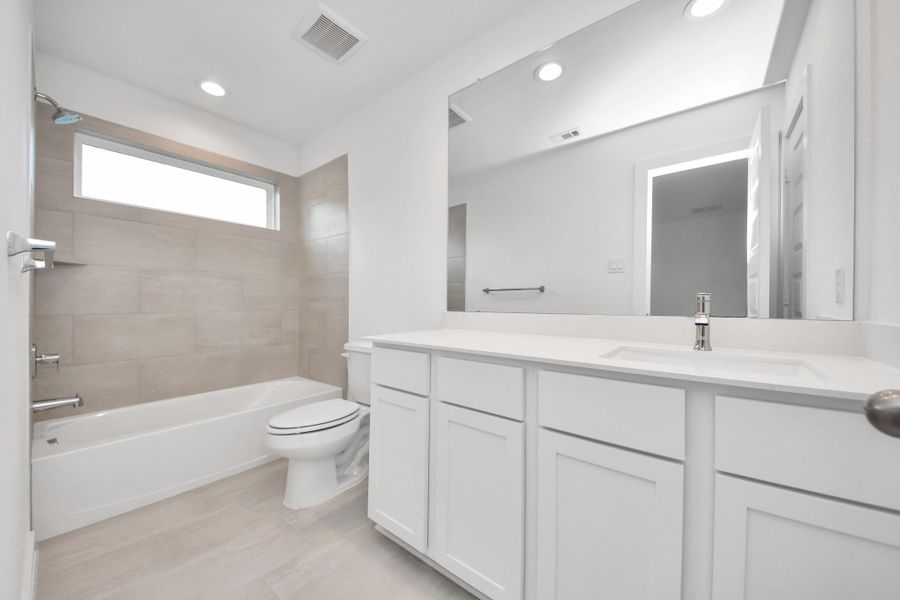 Secondary bath features tile flooring, bath/shower combo with tile surround, light stained wood cabinets, beautiful light countertop. Sample photo of completed home with similar floor plan. Actual colors and selections may vary. Secondary bath features tile flooring, bath/shower combo with tile surround, light stained wood cabinets, beautiful light countertop. Sample photo of completed home with similar floor plan. Actual colors and selections may vary.