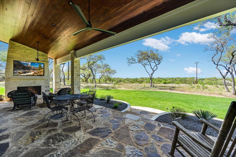 View of patio / terrace featuring an outdoor stone fireplace, outdoor dining space, and ceiling fan