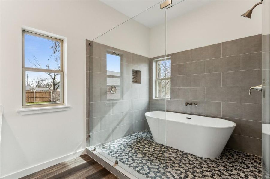 Bathroom with hardwood / wood-style floors, a bathing tub, a wealth of natural light, and tile walls