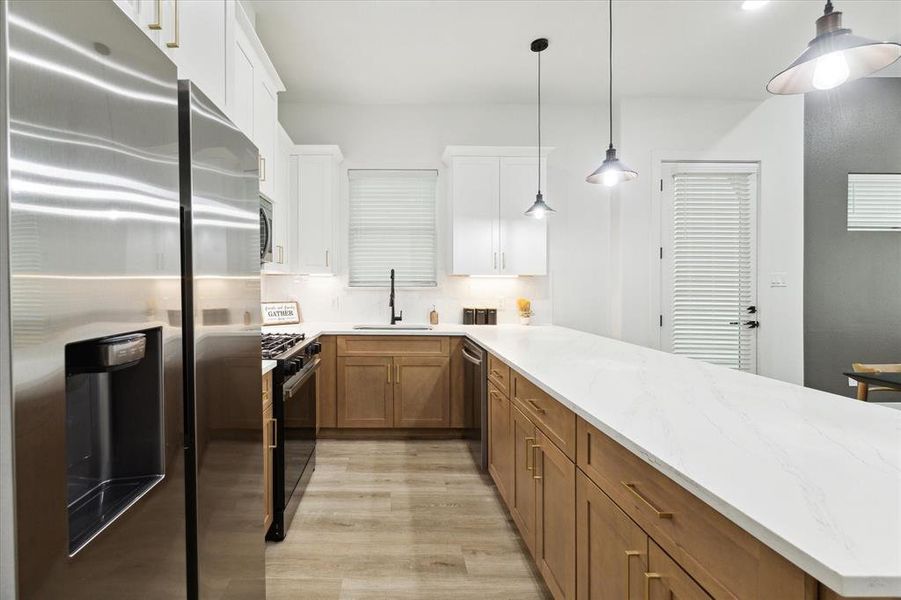 This additional kitchen angle highlights the expansive white countertops and ample cabinetry. A sleek stainless steel farmhouse sink, paired with dark plumbing hardware, adds a modern, sophisticated touch to the space.