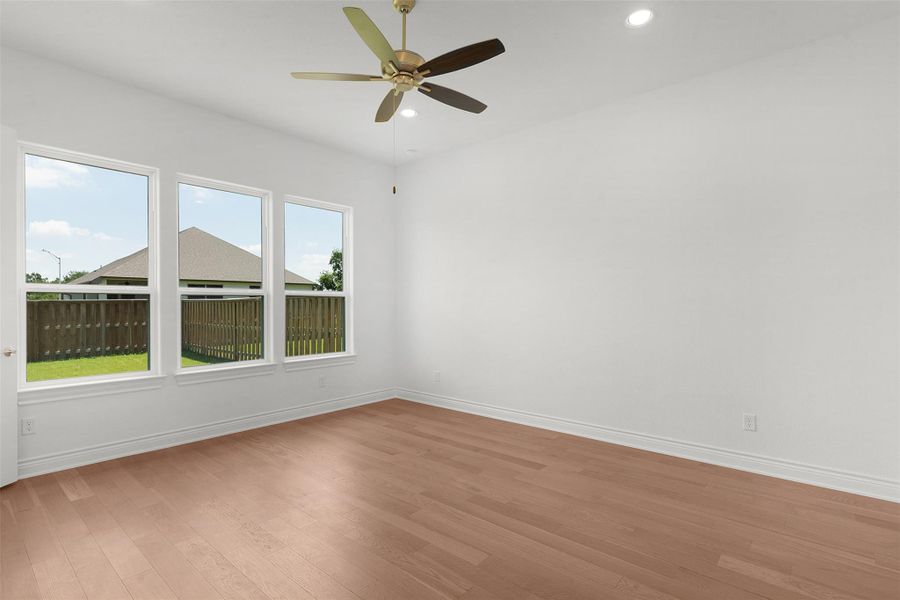 Expansive room featuring three large windows, wood-finish flooring, a ceiling fan with integrated lighting, and recessed lighting