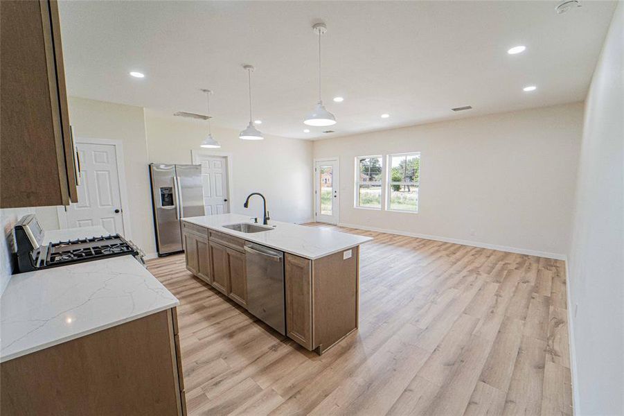 Open-concept living area featuring wood-finish flooring, recessed lighting, and ample natural light from multiple windows