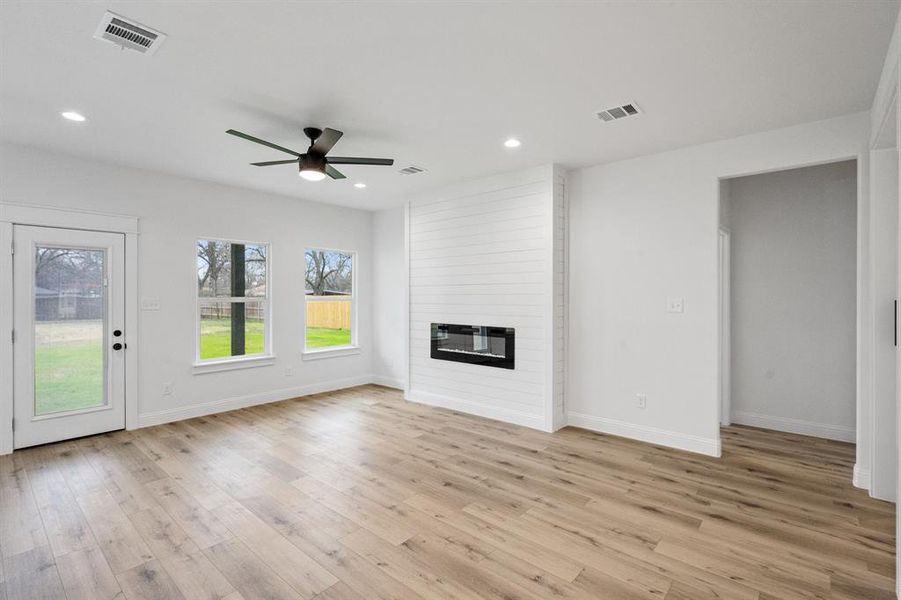 Unfurnished living room featuring a large fireplace, recessed lighting, visible vents, and light wood-style floors