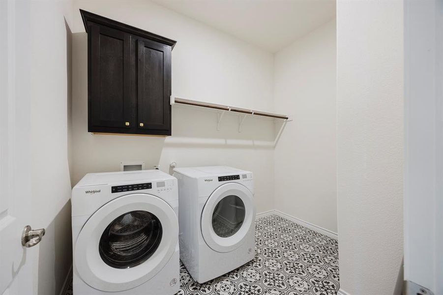 Laundry room with cabinets, light tile patterned floors, and washer and clothes dryer