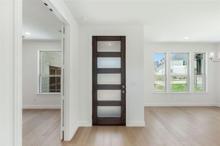 Entryway with dark wood door featuring frosted glass panels and light hardwood floors