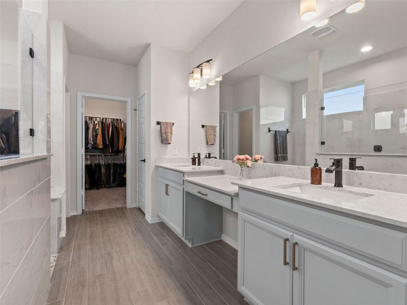 Full bathroom with a stall shower, double vanity, wood finish tiled floors, and a spacious closet