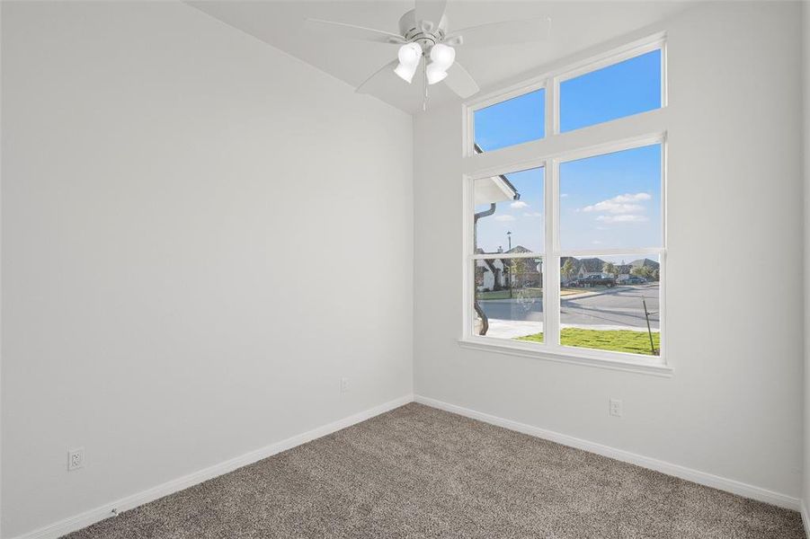 Empty room with a water view, carpet, and ceiling fan