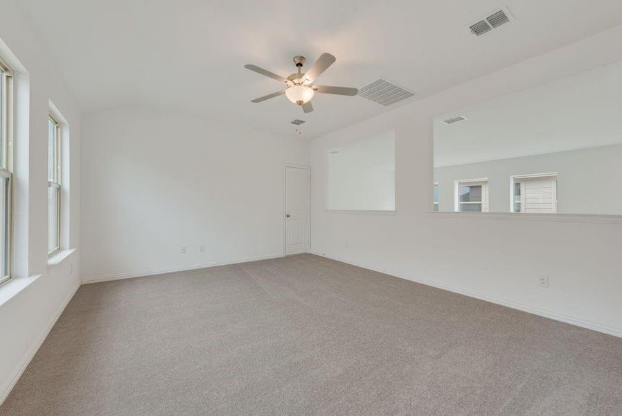 Empty room with light colored carpet, a ceiling fan, and plenty of natural light Empty room with light colored carpet, a ceiling fan, and plenty of natural light
