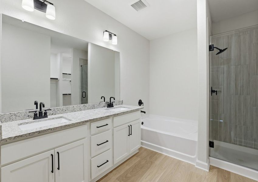 Primary bathroom featuring a double vanity, granite countertop, and a separate walk-in shower.