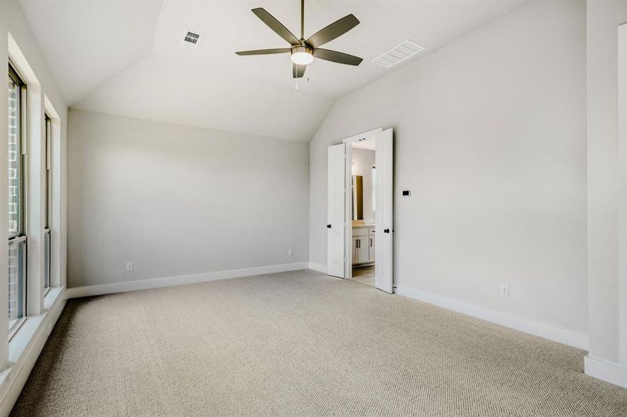 Unfurnished bedroom with carpet flooring, vaulted ceiling, a ceiling fan, and connected bathroom