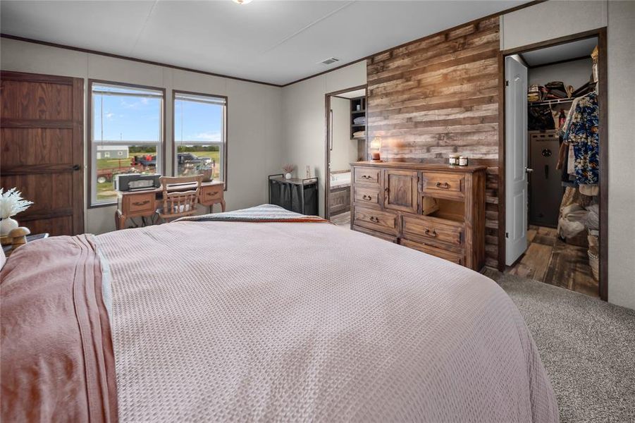 Carpeted bedroom featuring wood walls and a walk in closet Carpeted bedroom featuring wood walls and a walk in closet