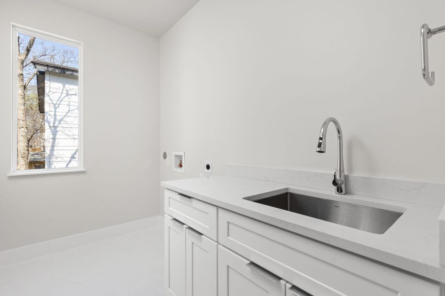 Kitchen featuring light stone counters, a healthy amount of sunlight, white cabinetry, and a sink