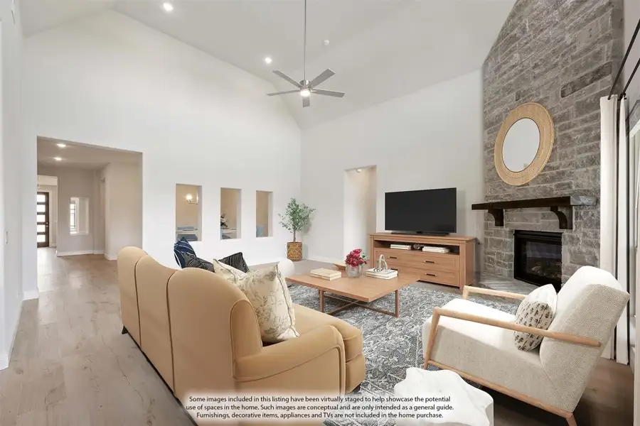 Living room with vaulted ceiling, stone fireplace, ceiling fan, and hardwood floors
