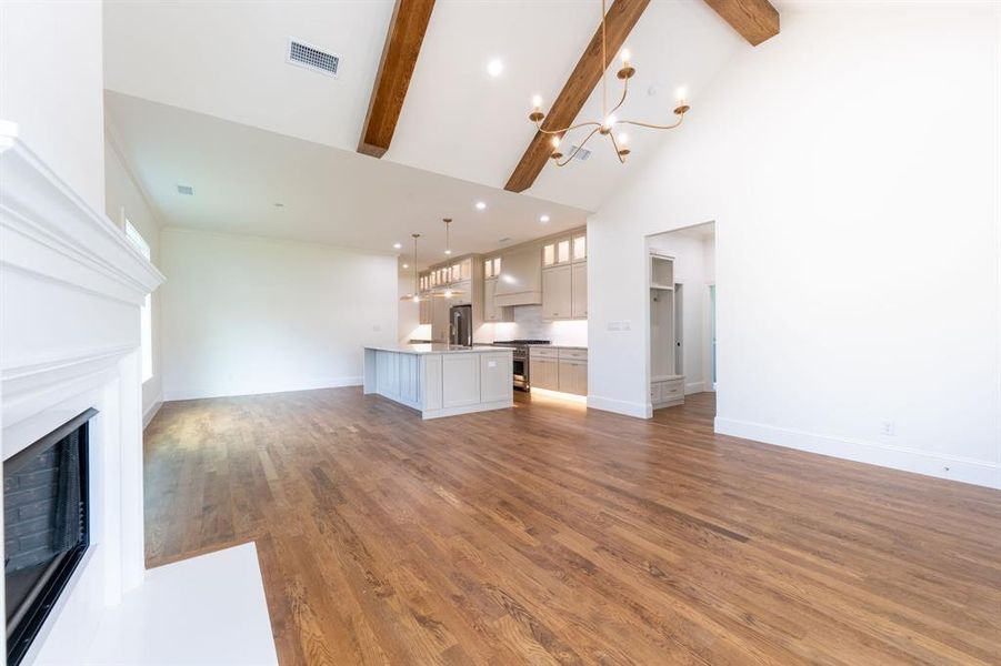 Spacious living area featuring high vaulted ceilings with exposed wood beams and a large chandelier Spacious living area featuring high vaulted ceilings with exposed wood beams and a large chandelier