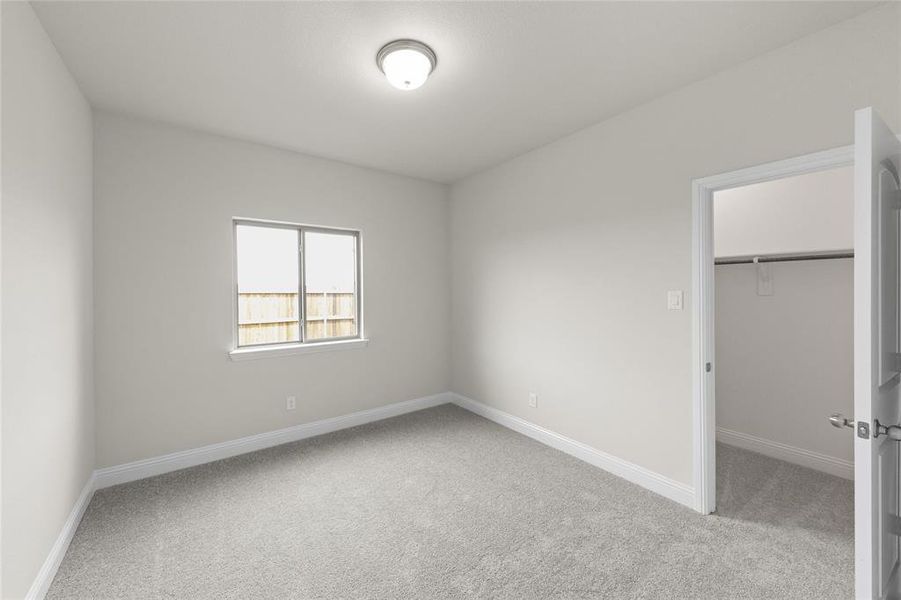 Unfurnished bedroom featuring a spacious closet, a closet, and light colored carpet