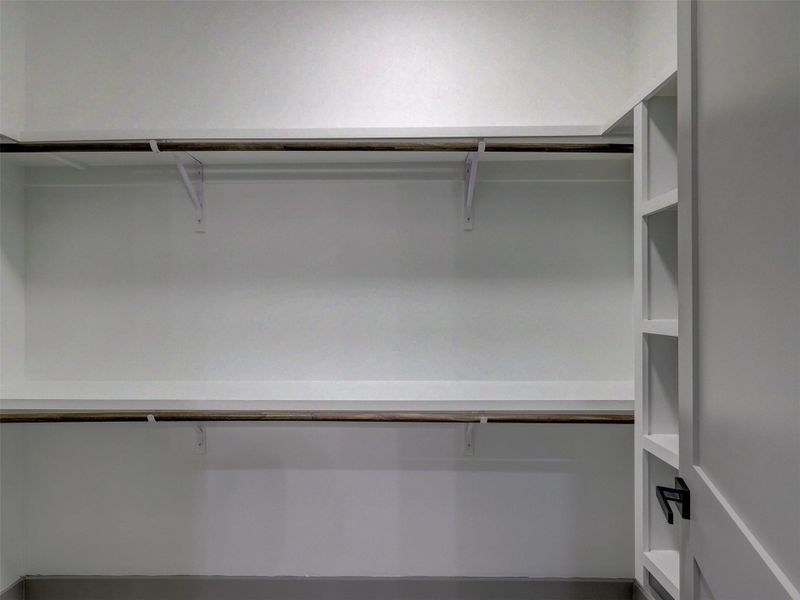 Ample built-in shelving and hanging rods maximize storage efficiency in this closet space.