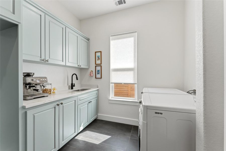 Laundry area featuring washer and dryer, cabinet space, and dark tile patterned flooring