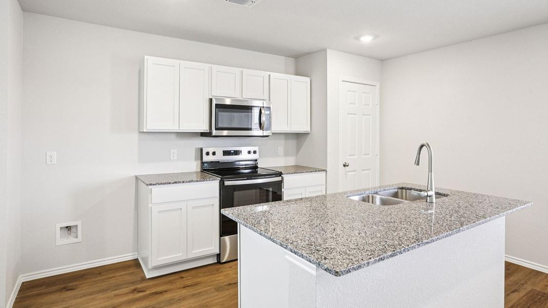 Kitchen featuring an island with a double basin stainless steel sink, a chrome gooseneck faucet, light-toned countertops, white cabinetry, and wood-finish flooring
