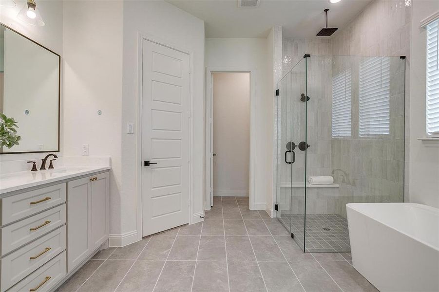 Primary Bathroom with vanity, walk in shower with standard shower head and rain head, freestanding tub, and large walk in shower