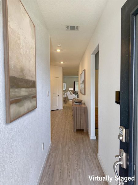 Enter into a welcoming hallway featuring resilient wood-look flooring and discreet recessed lighting.