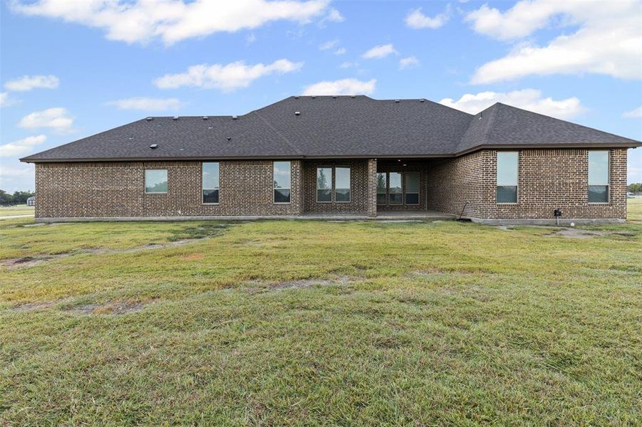 Back of house featuring brick siding, a patio area, a yard, and roof with shingles Back of house featuring brick siding, a patio area, a yard, and roof with shingles