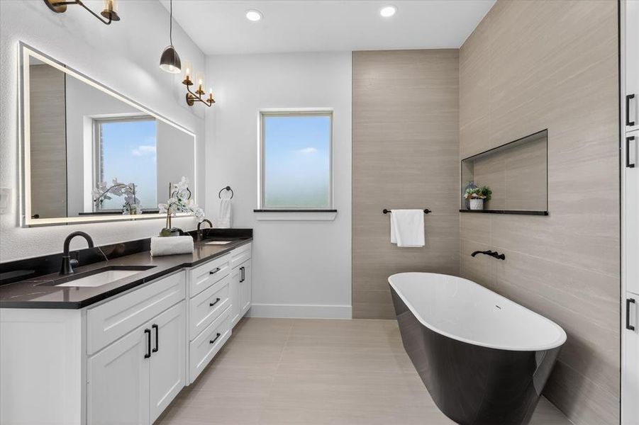 Full bathroom with double vanity, tile walls, a freestanding tub, recessed lighting, and light tile patterned floors