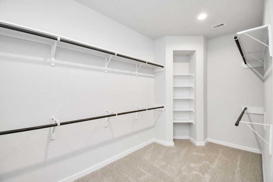 Walk-in closet that epitomizes luxury and practicality. This generously sized space features built-in shelving, offering abundant room for impeccable organization. High ceilings and recessed lighting create a bright and welcoming ambiance. Sample photo of completed home with similar floor plan. Actual colors and selections may vary.