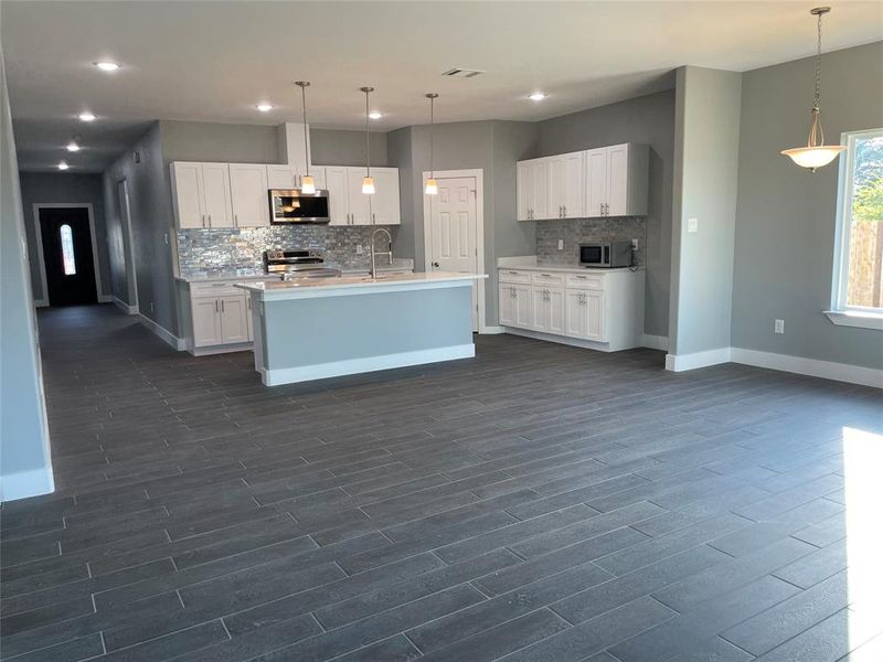 Kitchen featuring appliances with stainless steel finishes, white cabinets, dark hardwood / wood-style floors, and pendant lighting