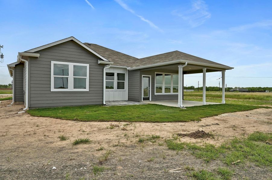 Back of house with a patio area, a yard, and roof with shingles