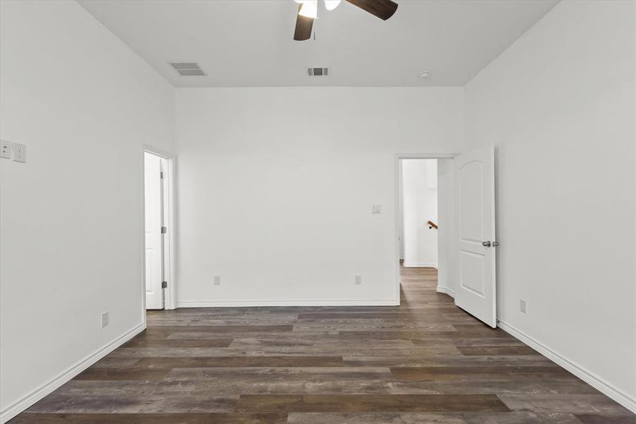 Spare room featuring dark wood-type flooring, a high ceiling, and ceiling fan