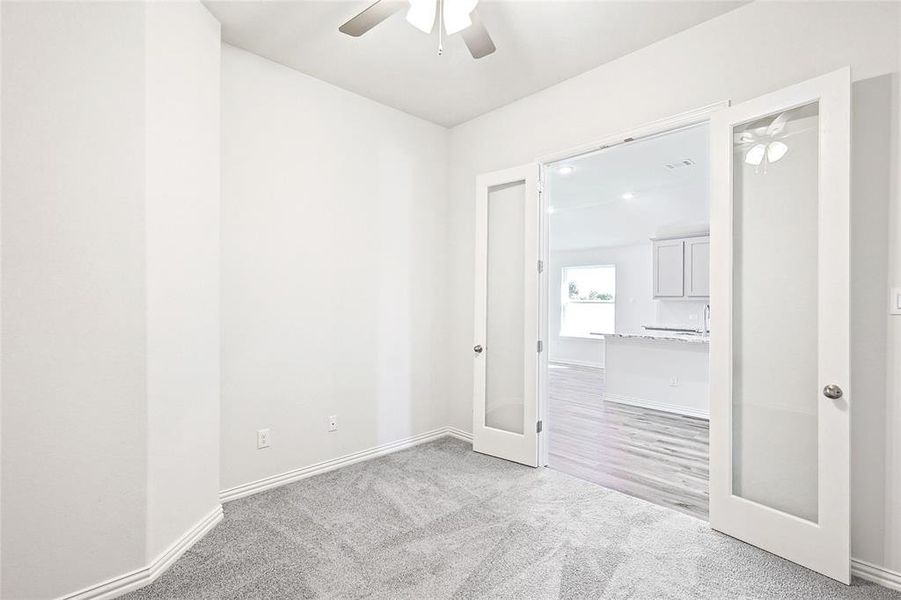 Spare room with ceiling fan, light colored carpet, and french doors