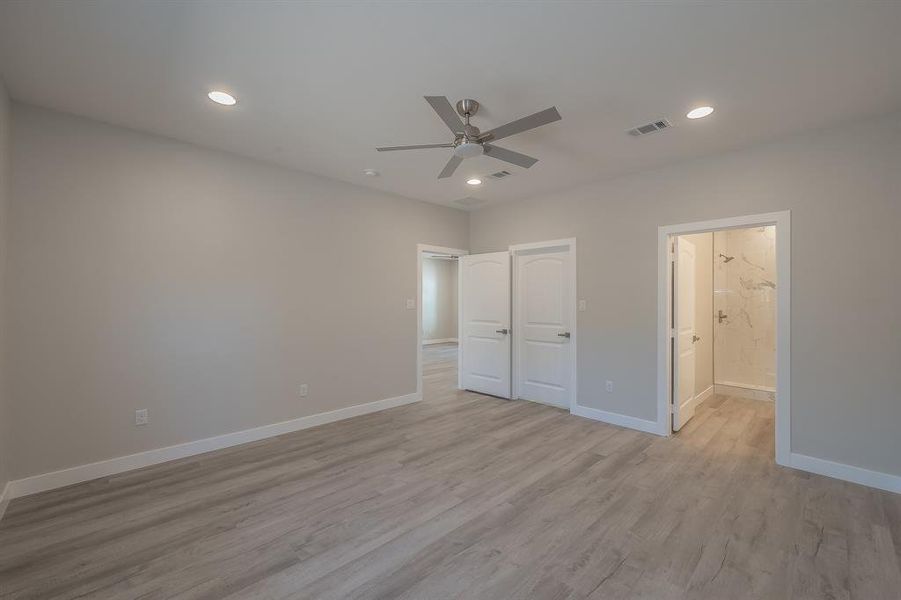 Unfurnished bedroom featuring light wood-style floors, ceiling fan, recessed lighting, and ensuite bathroom