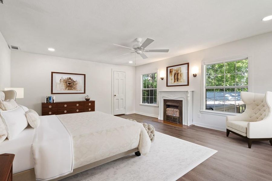 Bedroom featuring multiple windows, wood finished floors, recessed lighting, a high end fireplace, and baseboards