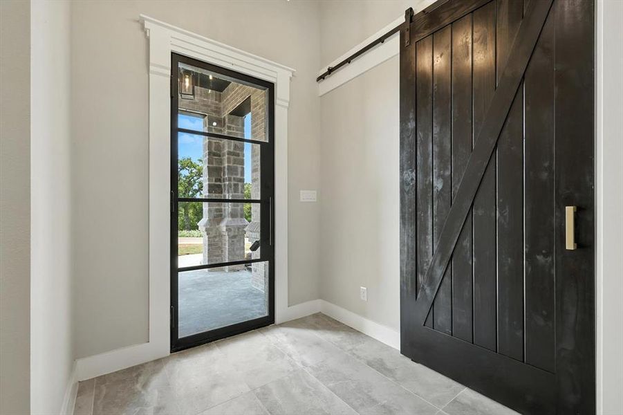Foyer entrance featuring a barn door and baseboards