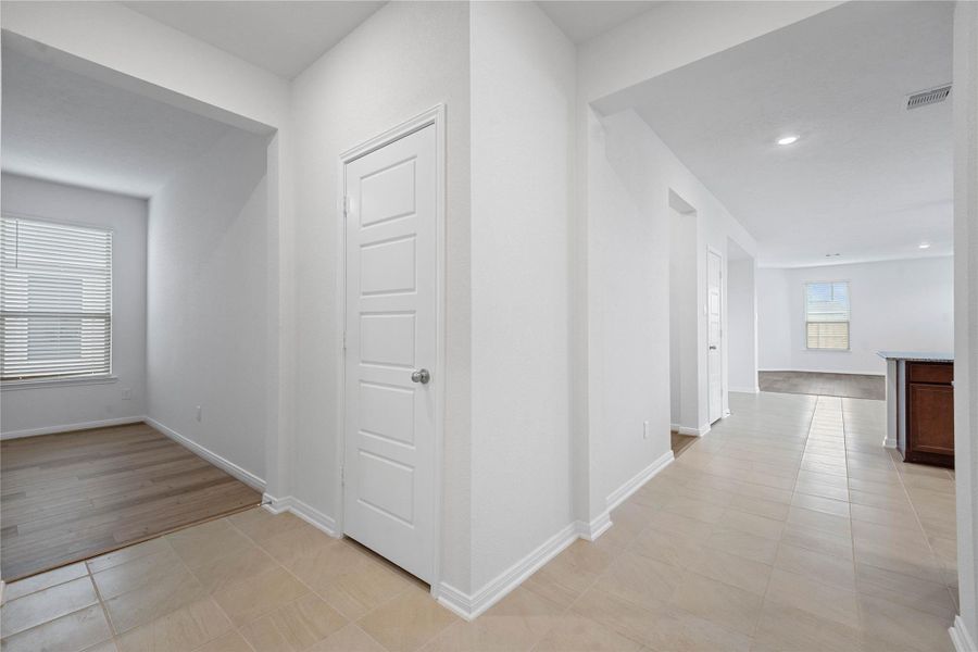 This view showcases the entrance to the Den, coat closet, laundry room, and entrance to kitchen and Great Room.