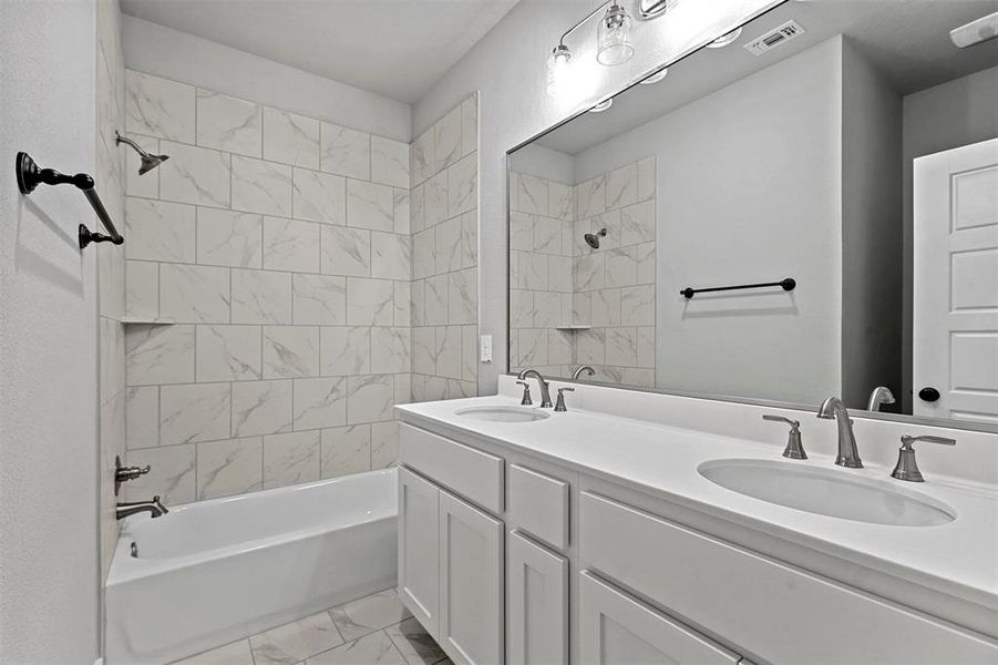 Bathroom featuring vanity and tiled shower / bath