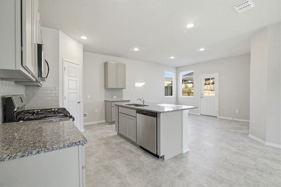 Image of a dining room overview with a granite kitchen center island, light grey walls, and tan tile flooring