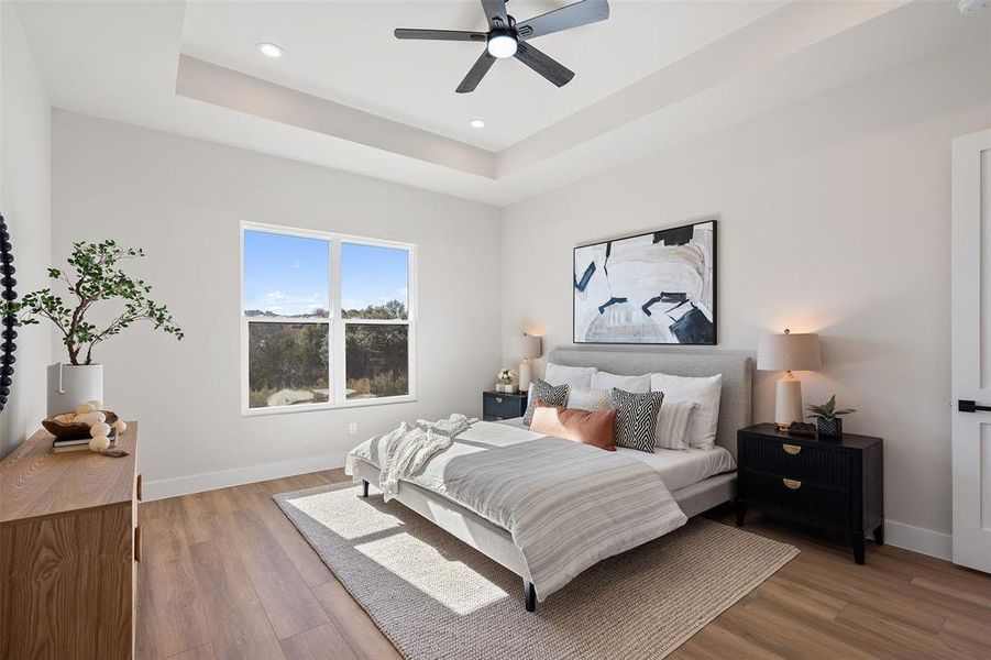 Bedroom featuring wood finished floors, a tray ceiling, a ceiling fan, and recessed lighting Bedroom featuring wood finished floors, a tray ceiling, a ceiling fan, and recessed lighting