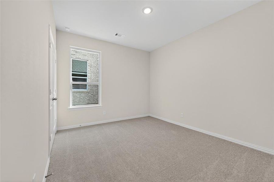 Empty room with light colored carpet and baseboards