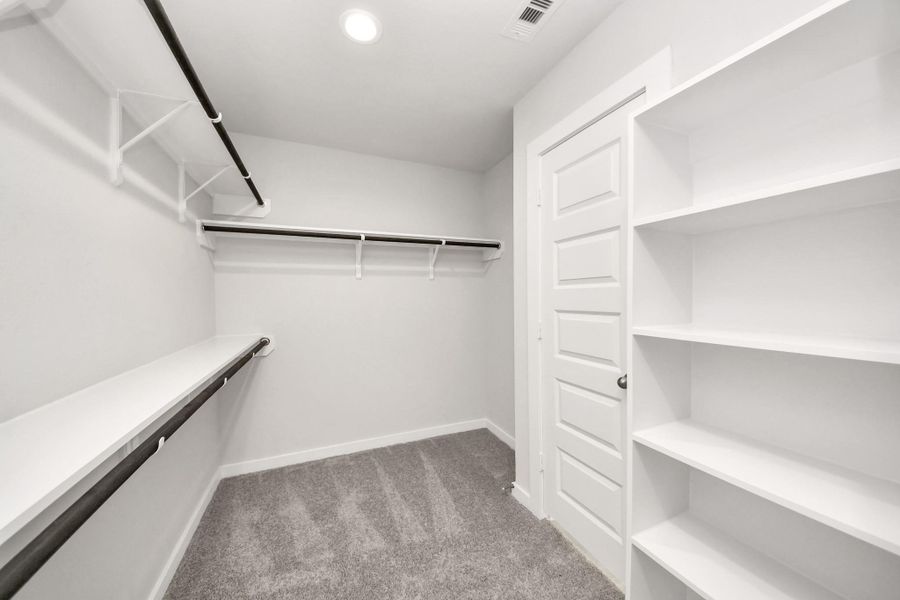 Walk-in closet that epitomizes luxury and practicality. This generously sized space features built-in shelving, offering abundant room for impeccable organization. High ceilings and recessed lighting create a bright and welcoming ambiance. Sample photo of completed home with similar floor plan. Actual colors and selections may vary. Walk-in closet that epitomizes luxury and practicality. This generously sized space features built-in shelving, offering abundant room for impeccable organization. High ceilings and recessed lighting create a bright and welcoming ambiance. Sample photo of completed home with similar floor plan. Actual colors and selections may vary.