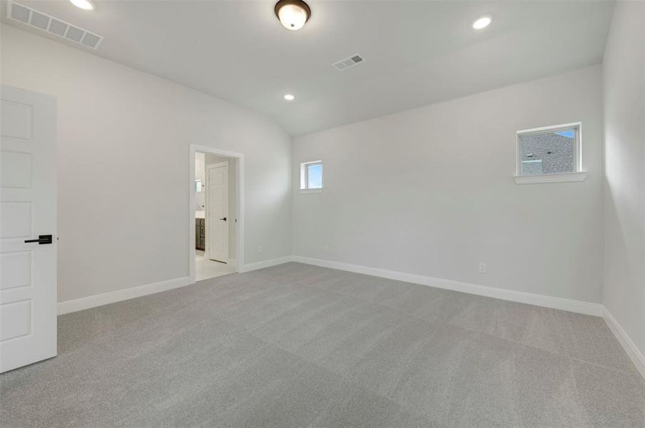Empty room with light carpet, vaulted ceiling, and recessed lighting